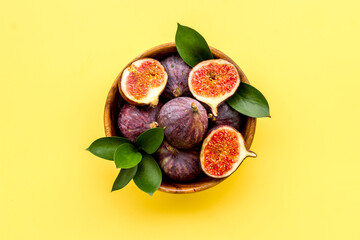 Fresh figs in a bowl with green leaves. Top view