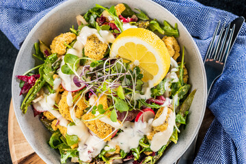 A plate of crispy Calamari Salad with lettuce, radish, lemon, tomatoes, asparagus and avocado.