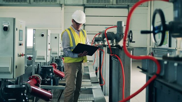 Factory worker is regulating indoor wastewater facilities