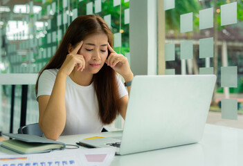 ..Asian business women look at laptops and Are stressed as the company's earnings have continued to decline. From the status of infectious disease that is spreading, business ideas and profit and loss