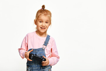 Cute kid girl playing video games holding gamepad and smiling , wearing pink casual sweatshirt and...