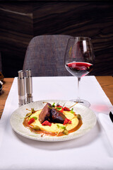 Meat dish with mashed potatoes and a glass of red wine