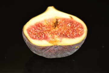 Ripe dark blue organic figs, close-up, on a black background.