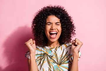 Photo portrait of cheerful girl screaming celebrating with fists up isolated on pastel pink colored background