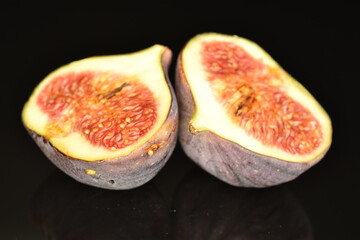 Ripe dark blue organic figs, close-up, on a black background.
