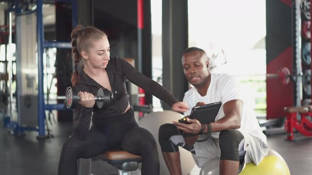 Sport woman in sportwear workouts with personal trainer at gym