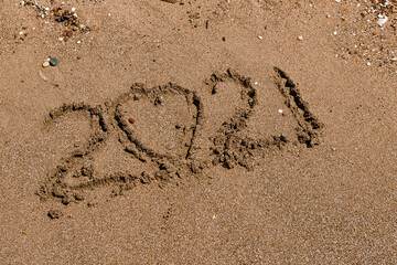number 2021 is written on the sand at sea.. 2021.heart in the sand. Two thousand twenty one