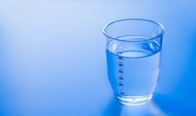 Measuring cup or cylinder on blue with copy space.