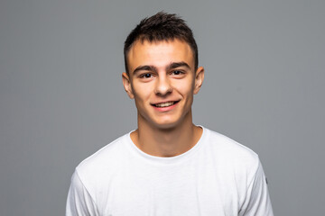 Portrait of a happy young man looking at camera over gray background