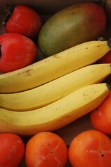 Fototapeta na wymiar Juicy persimmons bananas and mango close up 