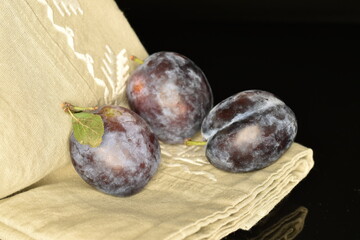 Ripe dark blue organic plums, close-up, on a black background.