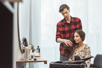 Stylist barber styling long hair for beautiful asian young woman in the beauty salon, working moment