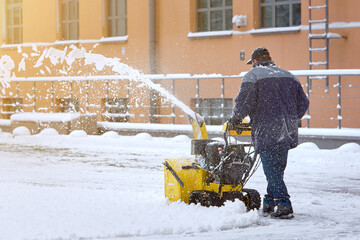 Worker with track drive snow blower removing deep snow, heavy duty assistant in winter season....