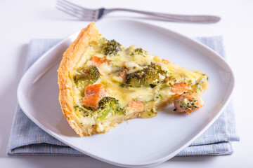 Quiche (open pie) with trout, broccoli and cheese. Homemade unsweetened pastries, traditional pie. Close-up.