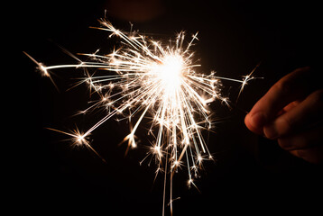 Burning sparkler in hand on a black background. New year, birthday