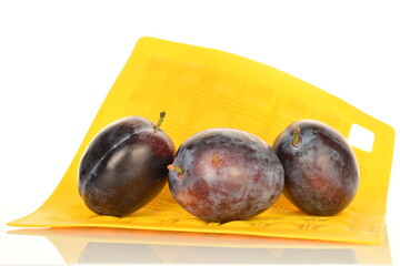 Ripe dark blue organic plums, close-up, on a white background.