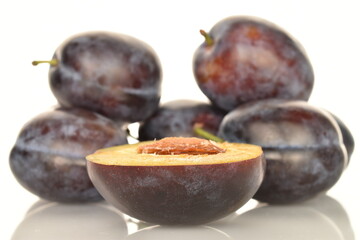 Ripe dark blue organic plums, close-up, on a white background.