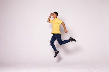 Young casual man celebrating his success and jumping over gray background.