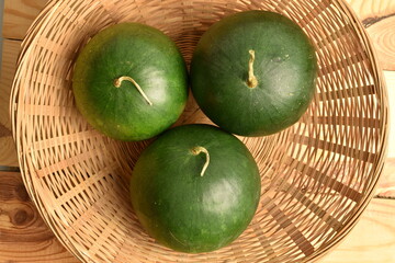 Three Ripe dark green organic watermelons, close-up, in a straw dish.