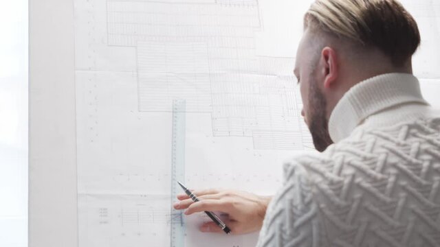 Concentrated architect works in loft using drawing board. Workplace of young engineer in modern office.