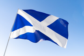 Flag of Scotland waving against blue sky