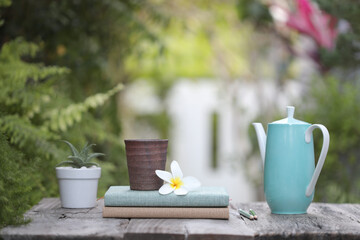 Old clay stone mug with flower and teal tea pot and succulent plants on old brown wooden table
