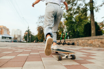 Photo in motion of a woman riding a longboard on the street, focus on the heel of sneakers. Female skateboarding concept.