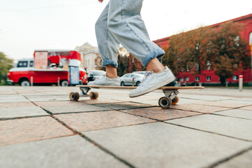 Close up blurred photo in motion, woman riding at speed on a longboard down the street against the backdrop of cityscape. Legs of a skater woman on a longboard walk. © bodnarphoto