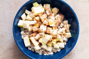 Blue oatmeal bowl with diced apples, honey and cinnamon