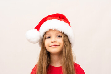 A beautiful little girl in a red t-shirt and a Christmas hat.