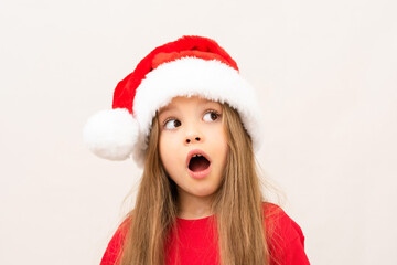A beautiful little girl in a Christmas hat opened her mouth in surprise.