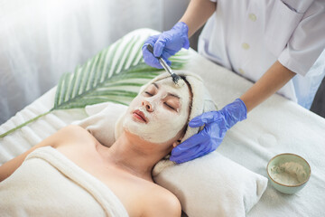 Obraz na płótnie Canvas Asian woman getting facial face care by beautician at spa salon.