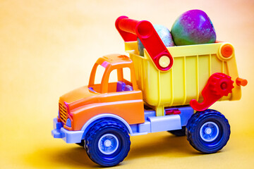 Toy truck on a yellow background with apples. Cargo transportation of fruit. 