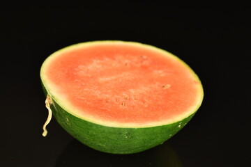 Sliced red organic watermelon, close-up, on a black background.