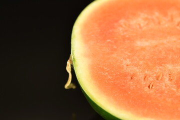 Sliced red organic watermelon, close-up, on a black background.