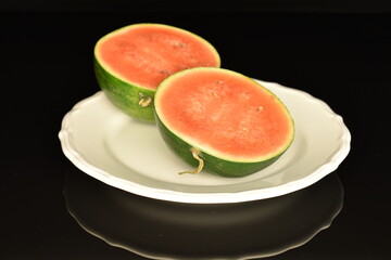 Sliced red organic watermelon, close-up, on a black background.