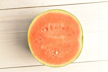 Sliced red organic watermelon, close-up, on a white wooden table.