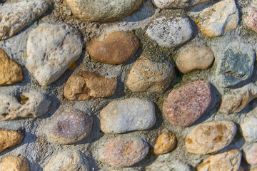Full frame stonework made of cobblestones of different colors and sizes as a backdrop.