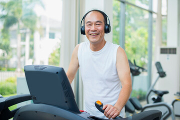 Senior asian man walking on treadmill in gym.