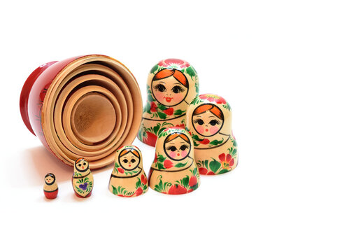 Heads from nesting dolls are lined up in a semicircle around the assembled lower part, lying on its side