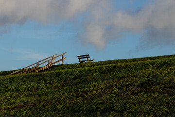 Park bench facing clouds green grass