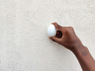 Hands holding an egg in white background.