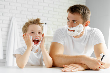 Father and little son having fun with shaving foam