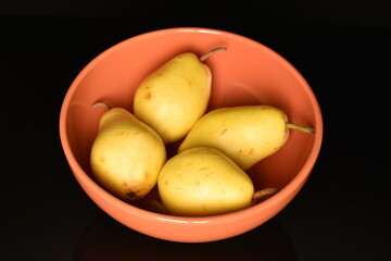 Ripe organic yellow-red pears, close-up, on a black background.