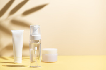 Set of cosmetic skin care products on yellow background with sunlight and shadows of leaves. Minimal style template
