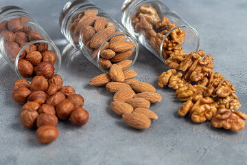 Almonds, walnuts and hazelnuts in a glass dish. Contains healthy vitamins and minerals. On a gray background.