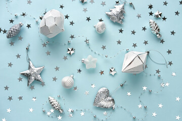 Christmas white and silver ornaments with sparkles on blue pastel background. Merry Christmas greeting card. Flat lay style.