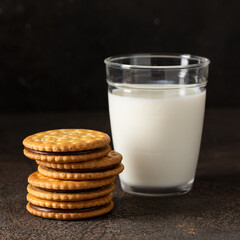 Sandwich biscuits cookies with chocolate filling with glass of milk on dark background for...