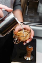 Fototapeta na wymiar Closeup of barista pouring milk into art cappuccino or latte