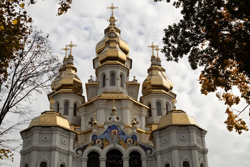 Fototapeta na wymiar A beautiful Christian church with many gilded domes among the autumn trees.